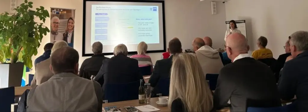 Gruppe von Menschen sitzen vor einer Präsentation